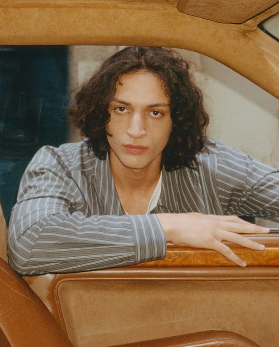 Man in a striped shirt leaning out of a car window, Organic Basics Men's Categories