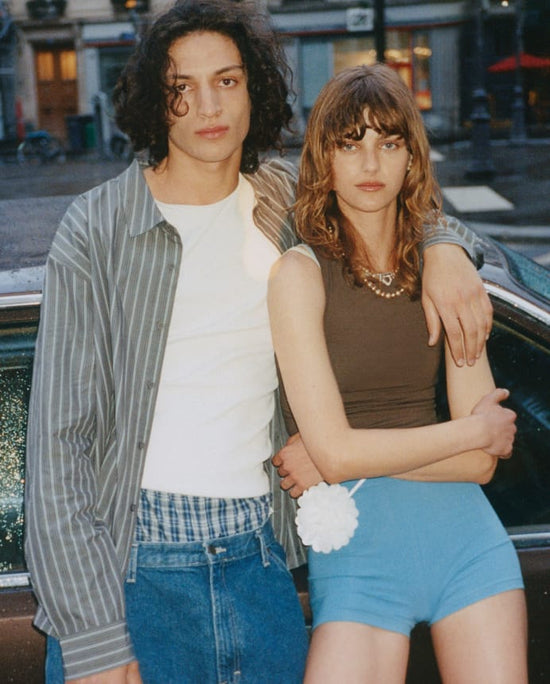 Man and woman in casual streetwear leaning against a car, Organic Basics Shop by Collection